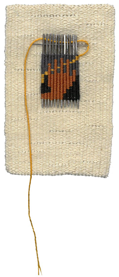 Cream background with additional woven section over needles. This section is of a hand over a thread. The thread is then continued through a needle threaded through the top of this section.